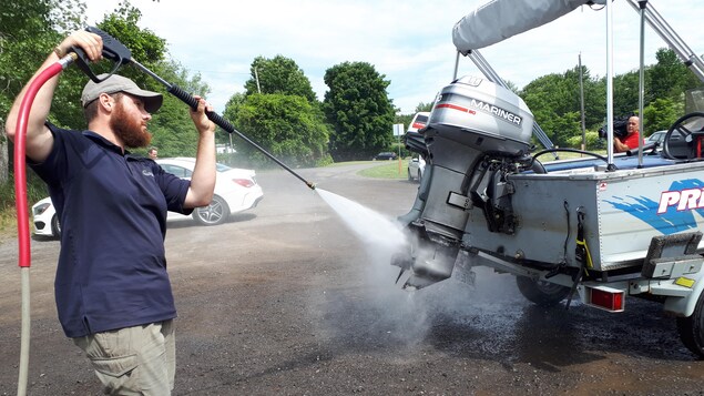 Un homme lave un bateau dans le cadre de cette activité de sensibilisation aux espèces aquatiques envahissantes.
