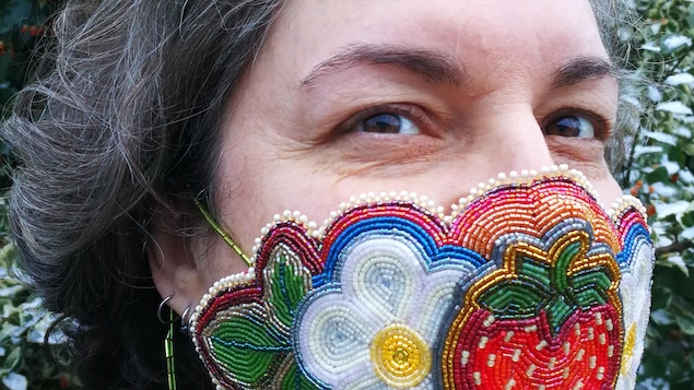 L'artiste métisse Nathalie Bertin porte sur son visage le masque qu'elle a conçu en broderie perlée qui signifie « Dis ta vérité. Toujours. » . On y voit une fraise géante et deux fleurs blanches de chaque côté.