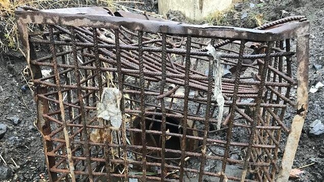 Une grille rudimentaire rouillée est disposée devant un tuyau servant à canaliser l'eau de fonte. Une grille rudimentaire rouillée est disposée devant un tuyau servant à canaliser l'eau de fonte.
