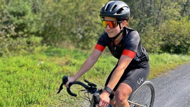 Carole Fournier fait du vélo sur une piste cyclable boisée.