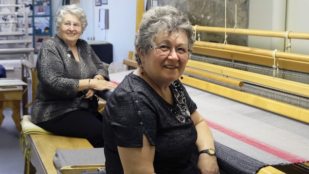 Deux femmes sourient devant une couverture. 
