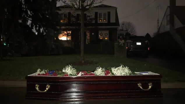 Un cercueil devant le jardin d'une maison, la nuit.