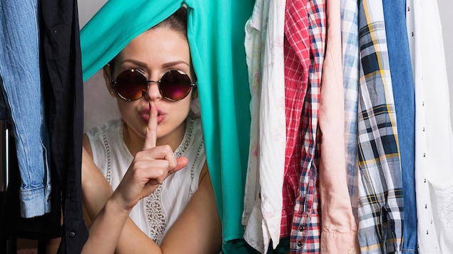 Une femme se cachant derrière des vêtements.