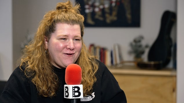 Coco Belliveau tient un microphone.