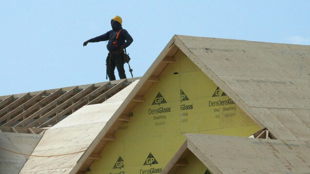 Un trabajador de la construcción en el tejado de una casa en construcción.