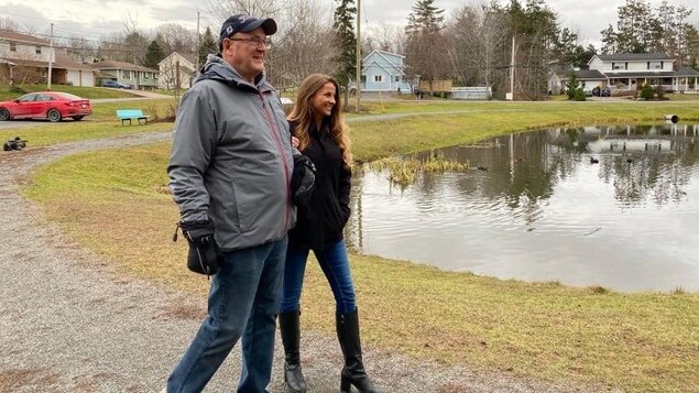 Kelly et Rick marchent en souriant au bord d'un lac.