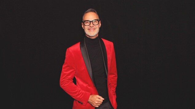 Daniel Simard posé avec un veston rouge