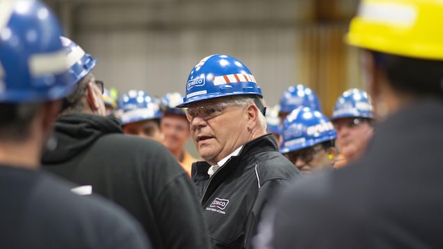 Doug Ford porte un casque de chantier et parle à des ouvriers.