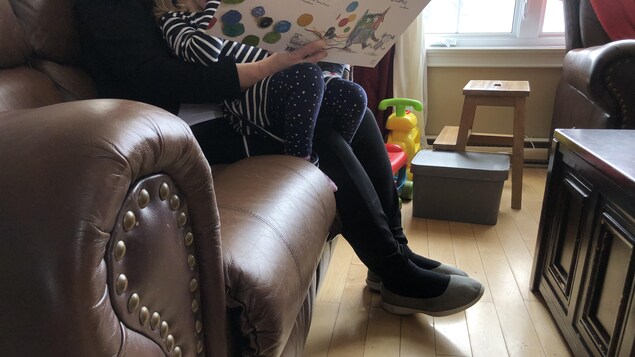 Une femme lit un livre à une enfant. 