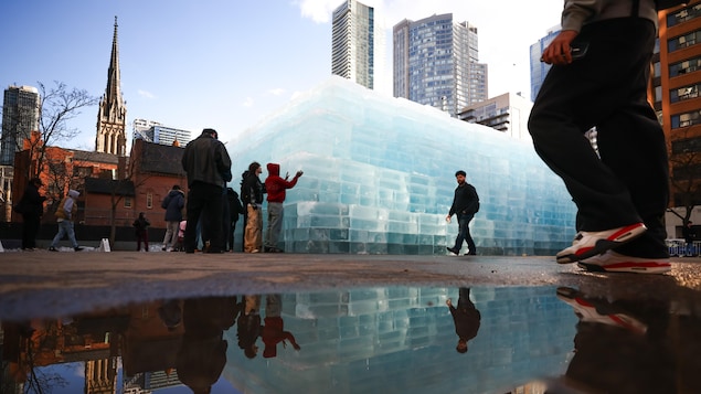 Des curieux observent une installation de glace dans un stationnement du centre-ville de Toronto.