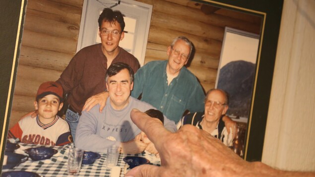 Une photo d'archives montrant Lucien Bouchard assis à table dans un chalet entouré de quatre personnes.