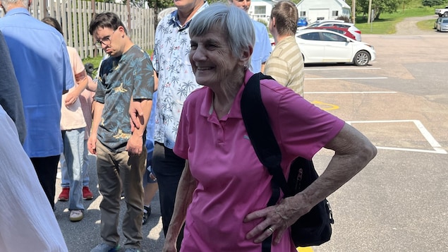 Louise Brissette à l'extérieur avec des gens derrière.