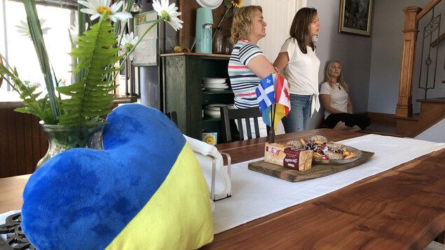 Un coussin aux couleurs du drapeau ukrainien est à l'avant-plan, on distingue aussi autour de collations un drapeau du québec et du canada. Trois personnes sont en arrière plan. 
