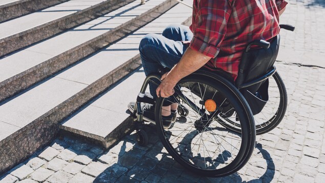 Une personne en fauteuil roulant qui fait face à un escalier.