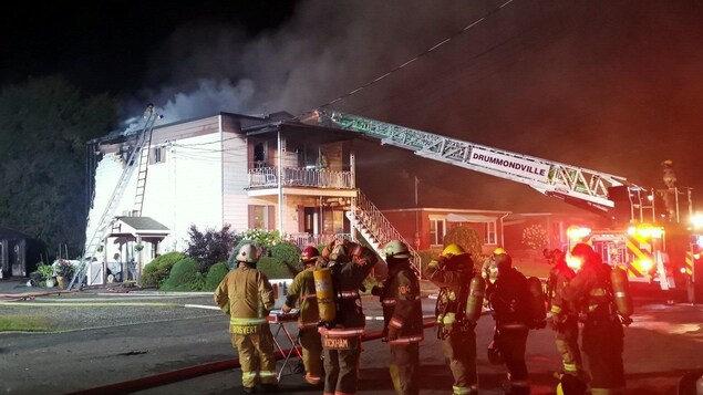 Des pompiers devant un édifice qui a brûlé.