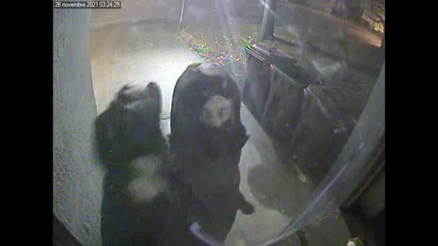 Un homme masqué est filmé par une caméra de surveillance. 