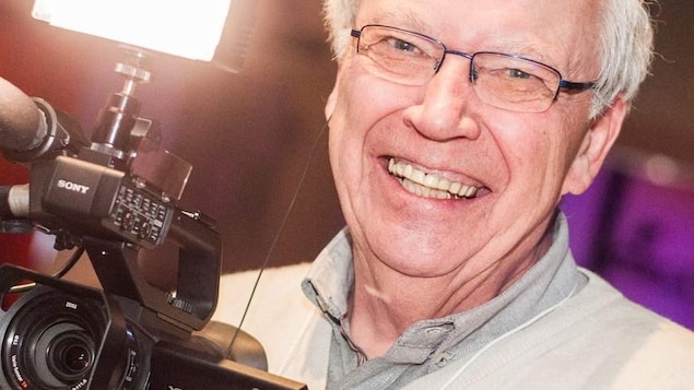 Pierre Javaux sourit avec une caméra