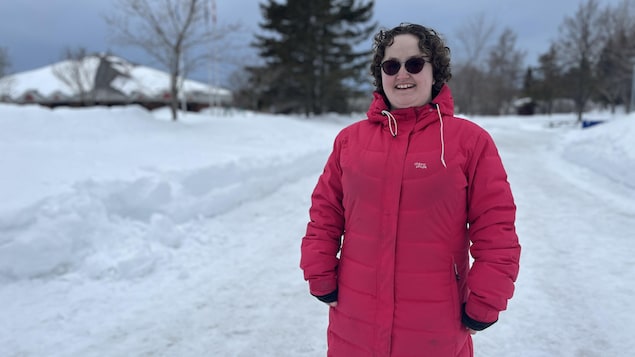 Julie Bourque en manteau d'hiver et lunette de soleil, dans un arrière-plan enneigé.