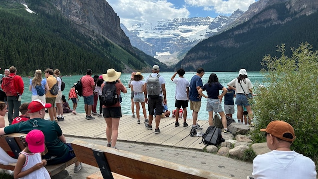 Nombreux toursites devant le lac Louise en trame de fond les montagnes avec très peu de neige. Ciel bleu avec un peu de nuages. Juillet 2024.