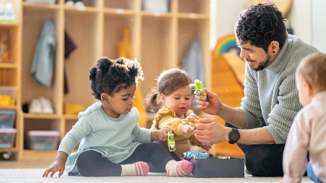 Un homme éducateur avec de jeunes enfants dans une garderie.