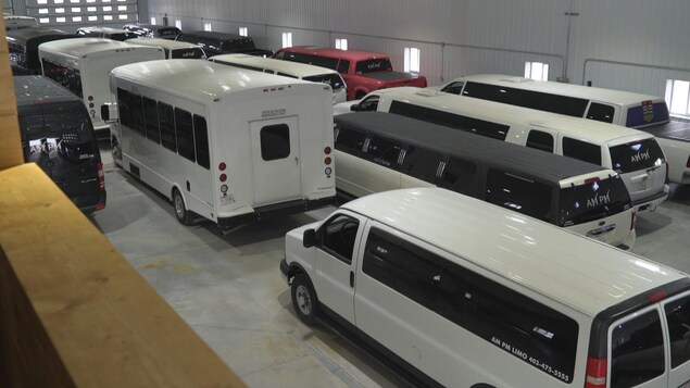 Plusieurs limousines et autobus de fête stationnés dans un garage.