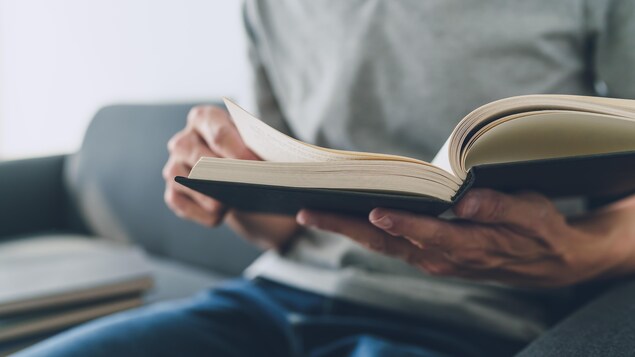 Gros plan d'un homme qui lit un livre.