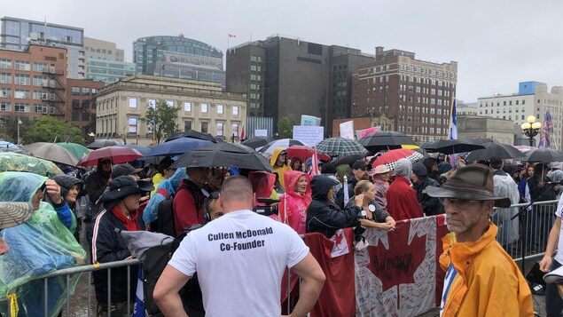 Foule de manifestants derrière des barrières de sécurité.