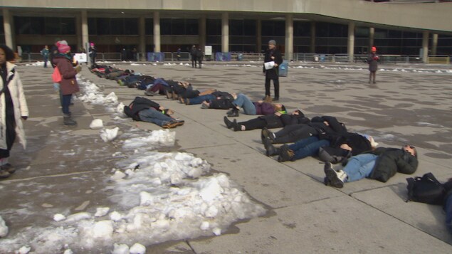 Des personnes sont allongées au sol devant l'hôtel de ville de Toronto.