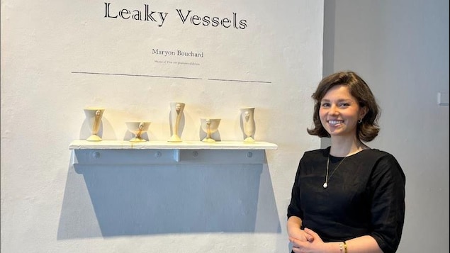 Maryon Bouchard devant l'affiche de son exposition Leaky Vessels.