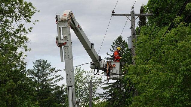 Un monteur de ligne d'Hydro-Québec fait des réparations sur les fils électriques.