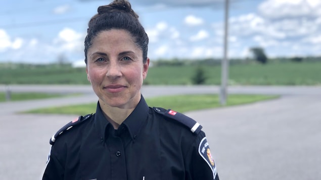 Une femme en uniforme souriante devant la caméra.