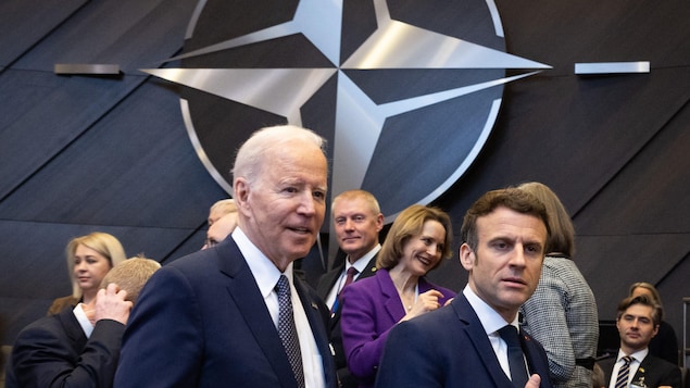 Le président des États-Unis, Joe Biden et le président de la France, Emmanuel Macron en dessous du logo de l'OTAN.