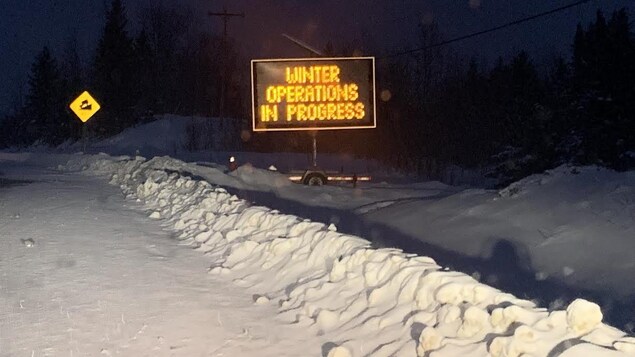 Un panneau routier indiquant des opérations de dénaigement en hiver sur le bord d'une route.