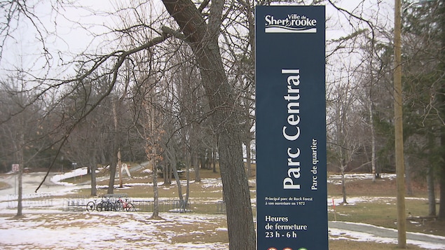 Une affiche du Parc central devant un champ et des arbres.