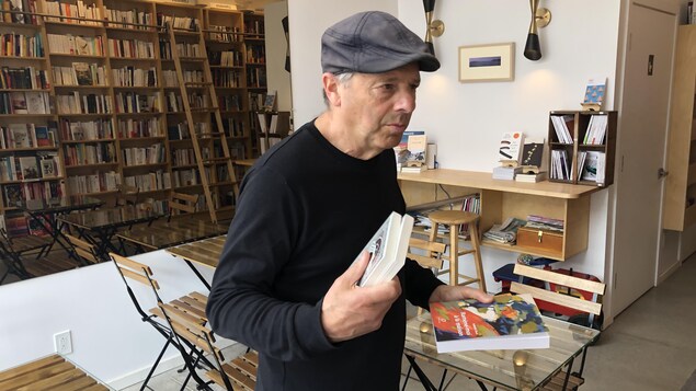 Un homme tient des livres dans ses mains dans une librairie.