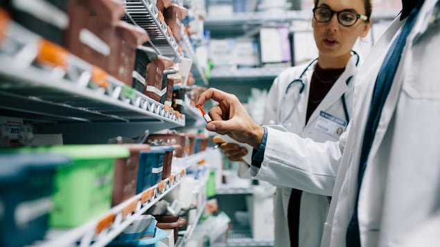Deux pharmaciens en milieu hospitalier qui regardent l'état des stocks de médicaments.