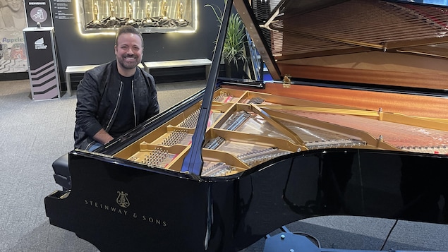 Un homme assis devant un piano à queue de marque Steinway & Sons.