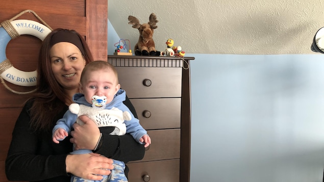 Une femme tient son bébé de cinq mois.