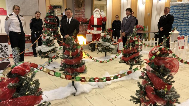Des membres de l'équipe des pompiers de Drummondville sourient devant des décors de Noël.