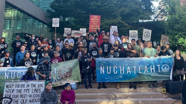 Des membres de la Nation Nuchatlaht sur les marches de la cour suprême de la Colombie-Britannique avec des banderolles.