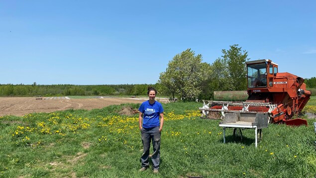 Rébéka Frazer-Chiasson devant un champ et de la machinerie de ferme.