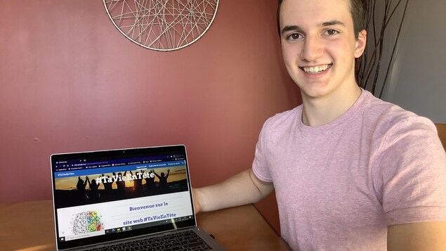Renaud St-Onge souriant aux côtés d'un ordinateur portable.