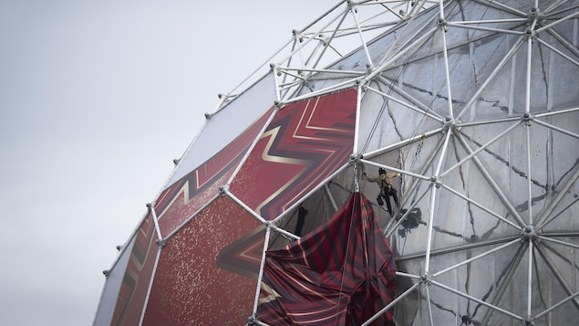 Des travailleurs enlèvent les panneaux du ballon de soccer de la Coupe du Monde de la FIFA de l'édifice Science World.