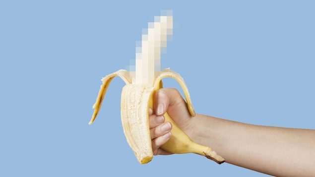 Gros plan d'une main qui tient une banane dont la partie du au est pixelisée.