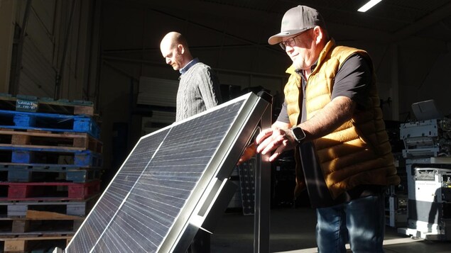 Darren Dunfield et Mark Schell poussent un panneau solaire incliné vers le soleil.