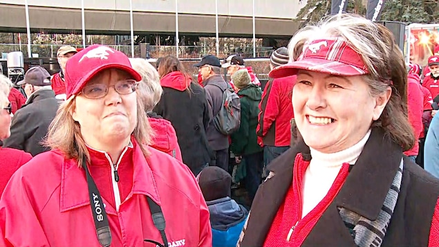 Deux femmes portant des casquettes sourient. Deux femmes portant des casquettes sourient.