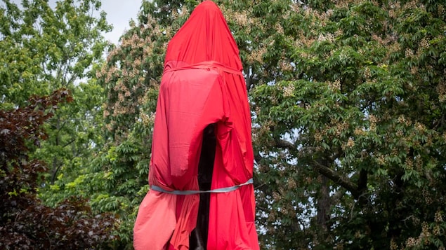 Une statue recouverte d'un drap rouge.