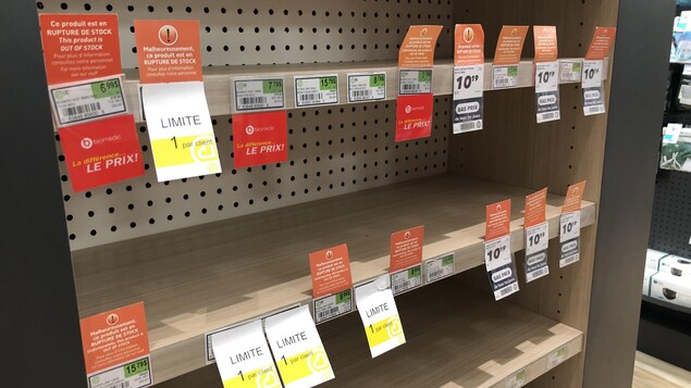 Des tablettes vides. Des affiches indiquent « limite de un par client ».