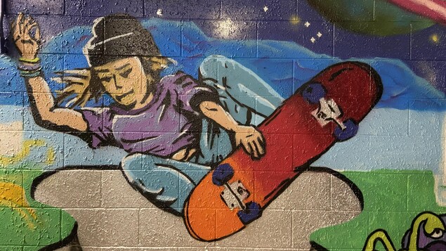 Une peinture murale d'un jeune faisant de la planche à roulette.