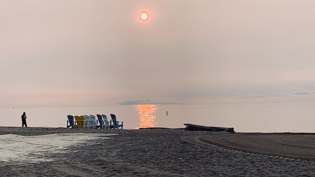 Le soleil paraît orangé dans un ciel couvert par un voile de particules fines.